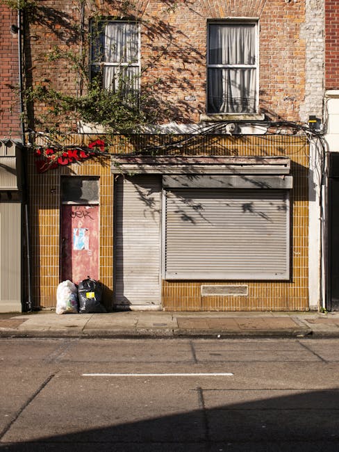 A close-up view of a red brick wall with a rectangular white sign attached to it. The sign displays the message 'NO DUMPING OF RUBBISH' in black uppercase letters, with the word 'DUMPING' partially ob